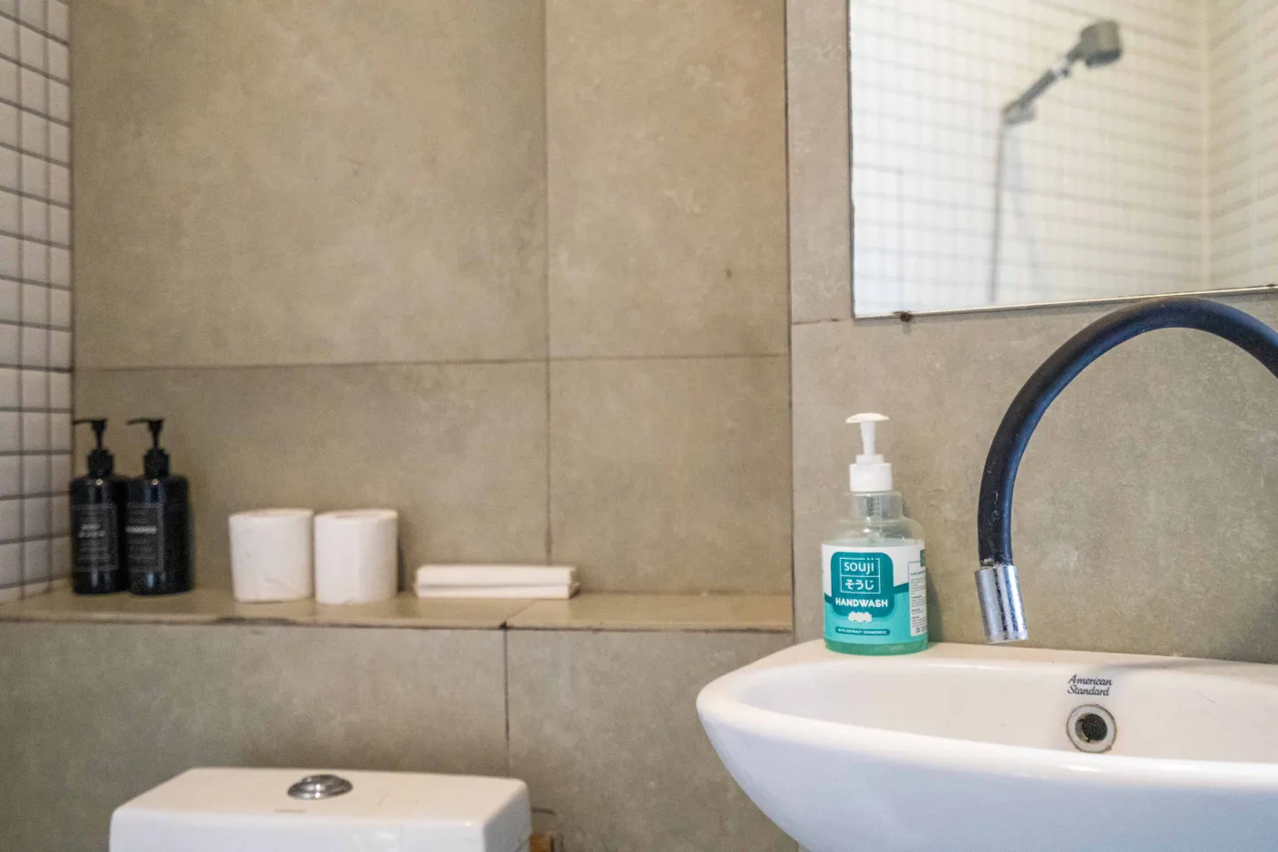 Modern white-tiled bathroom with glass shower enclosure, sink, and toilet. - Bali Villas