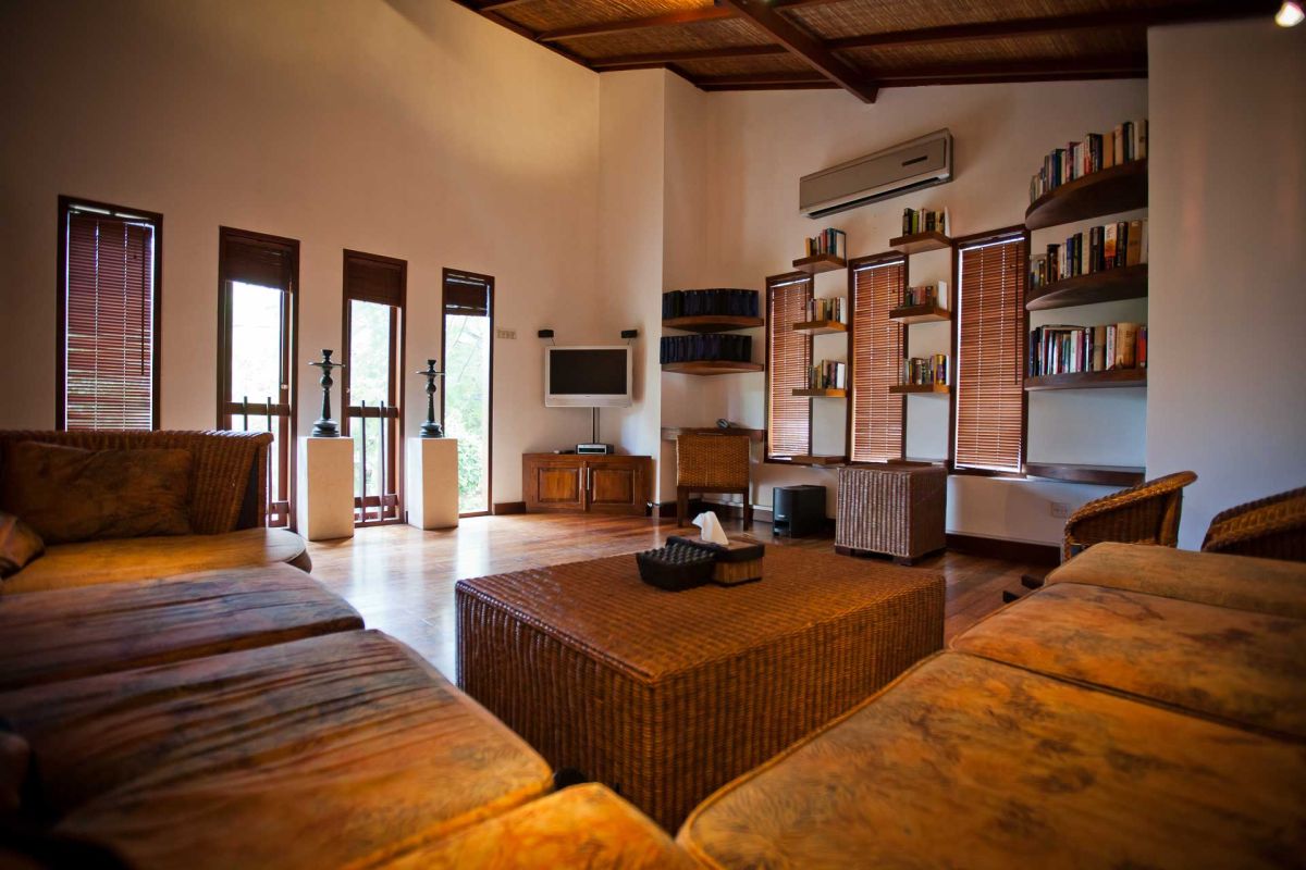 Luxurious Balinese villa rooftop terrace with green lounge chairs, white towels, potted frangipani trees, and sliding glass doors under a clear blue sky. - Bali Villas