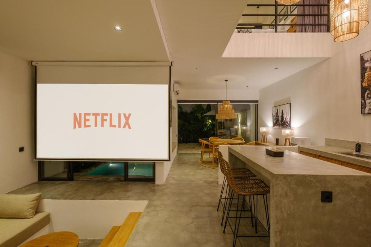 Modern tropical villa plunge pool with lounge daybed, parasol, and lush greenery. - Bali Villas