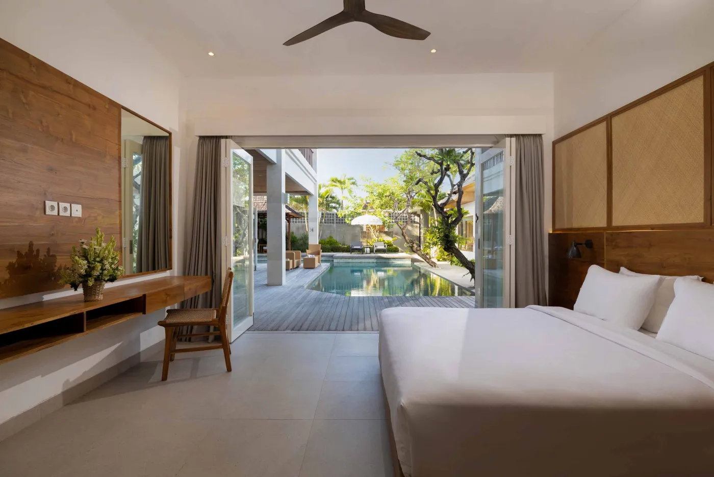 Modern wooden kitchen with marble island, black fridge, pendant lights, and tropical decor. - Bali Villas