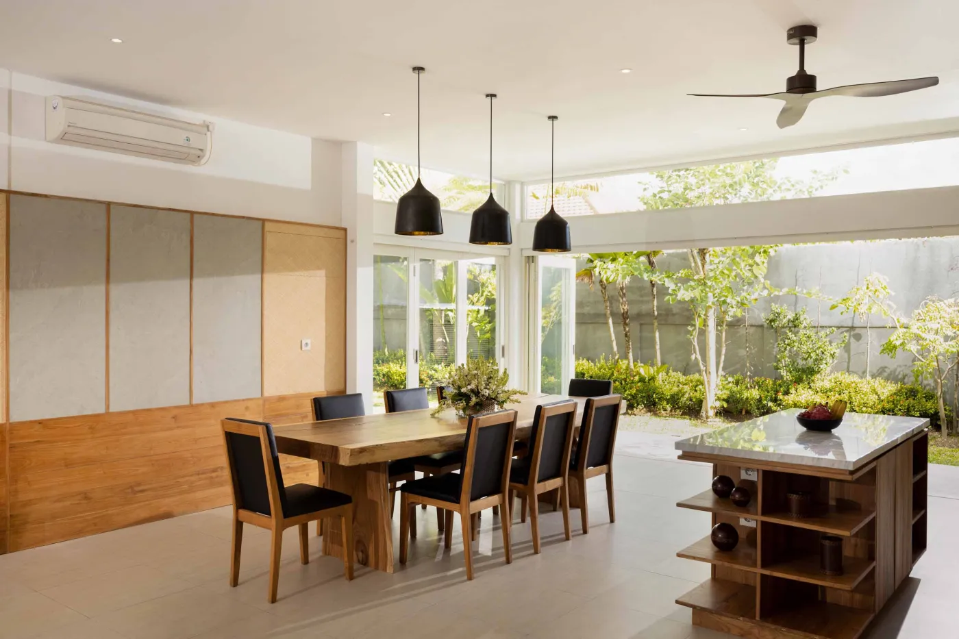 Modern wooden kitchen with marble island, black fridge, pendant lights, and tropical decor. - Bali Villas