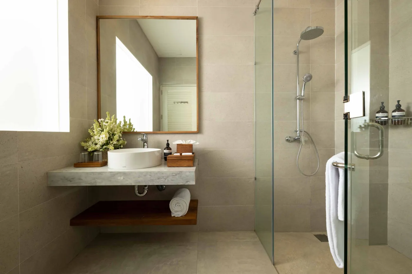 Modern wooden kitchen with marble island, black fridge, pendant lights, and tropical decor. - Bali Villas