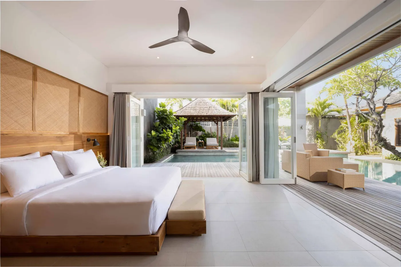 Modern wooden kitchen with marble island, black fridge, pendant lights, and tropical decor. - Bali Villas