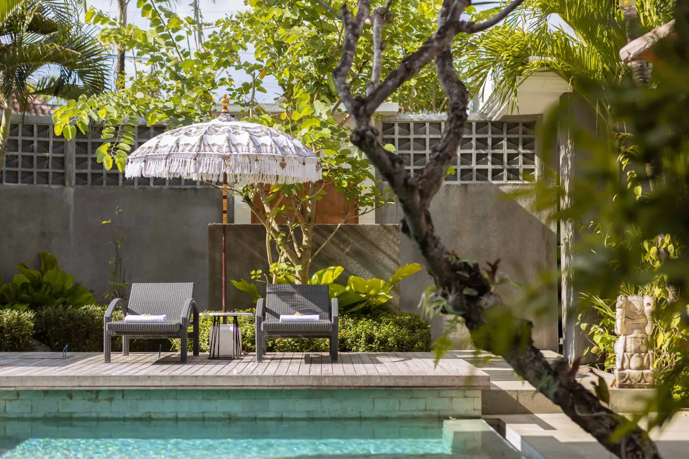 Modern wooden kitchen with marble island, black fridge, pendant lights, and tropical decor. - Bali Villas