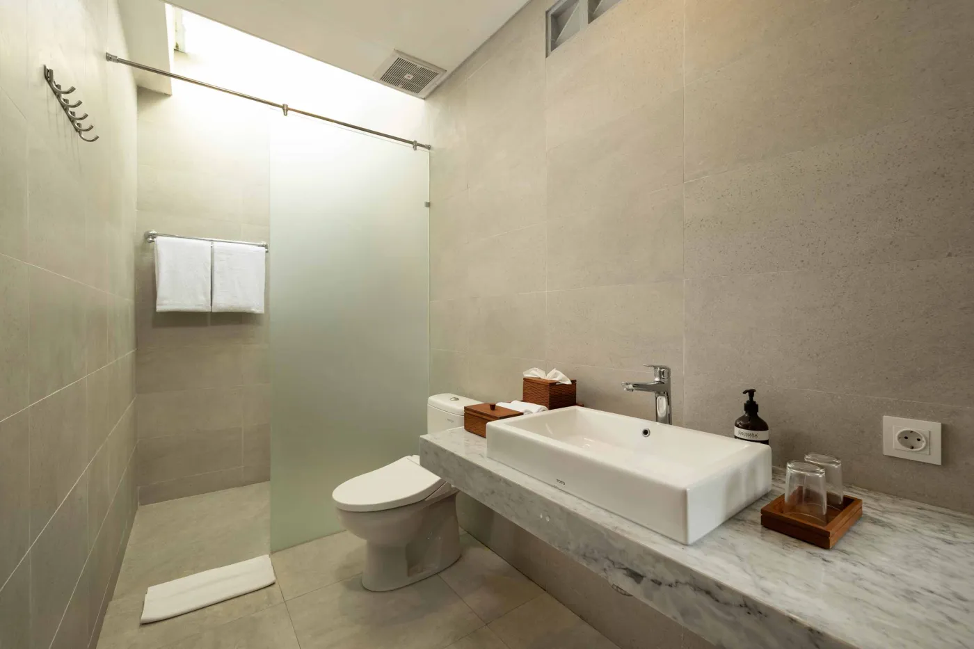 Modern wooden kitchen with marble island, black fridge, pendant lights, and tropical decor. - Bali Villas