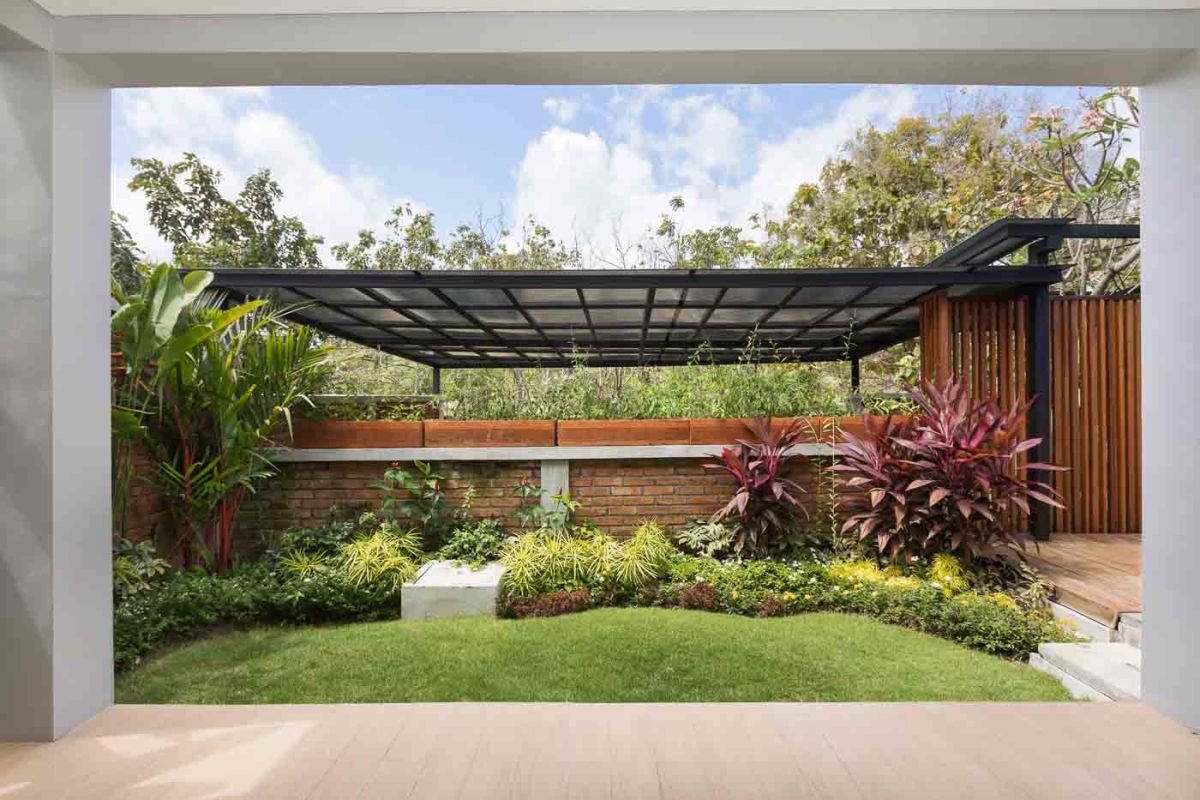 Elegant open-plan dining room in a luxury Balinese villa, featuring a glass-top table with rattan chairs, tropical centerpiece, sleek kitchen, and poolside views. - Bali Villas