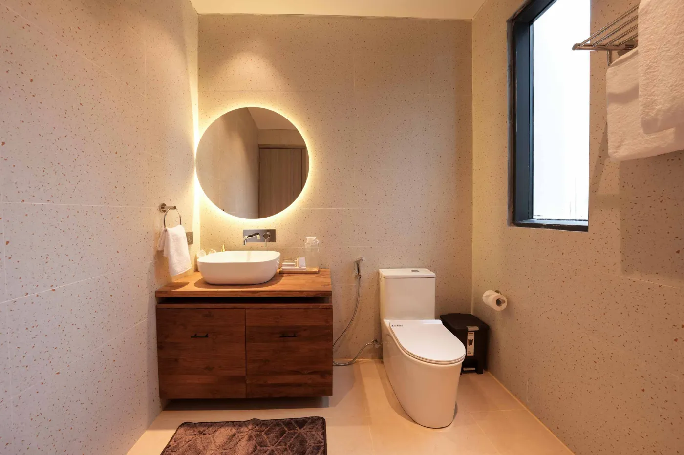 Modern wooden kitchen with stainless steel sink, refrigerator, microwave, cooktop, and warm LED lighting. - Bali Villas