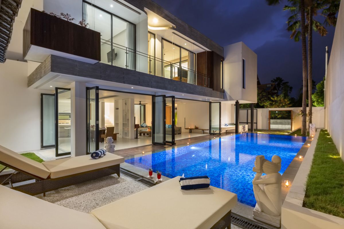 Modern white kitchen with island countertop, gas stove, stainless sink, and tropical orchid accents. - Bali Villas