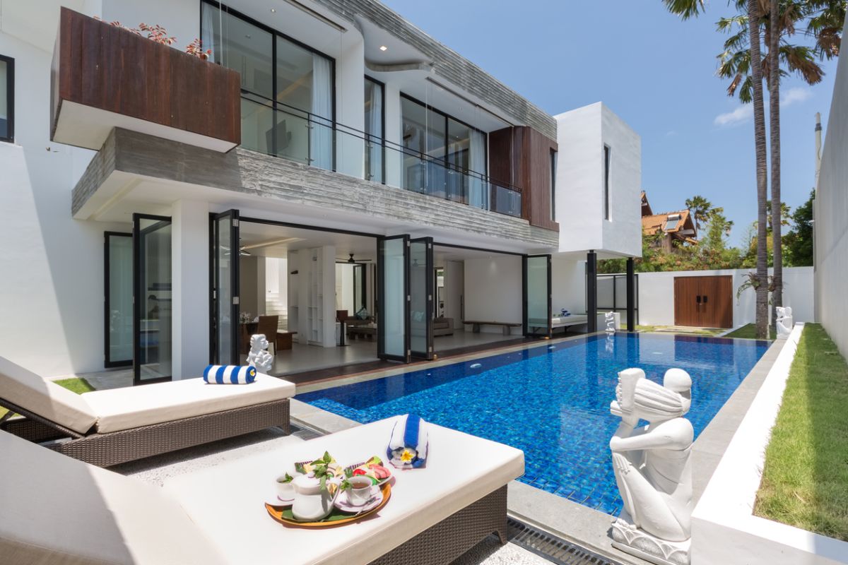 Modern white kitchen with island countertop, gas stove, stainless sink, and tropical orchid accents. - Bali Villas