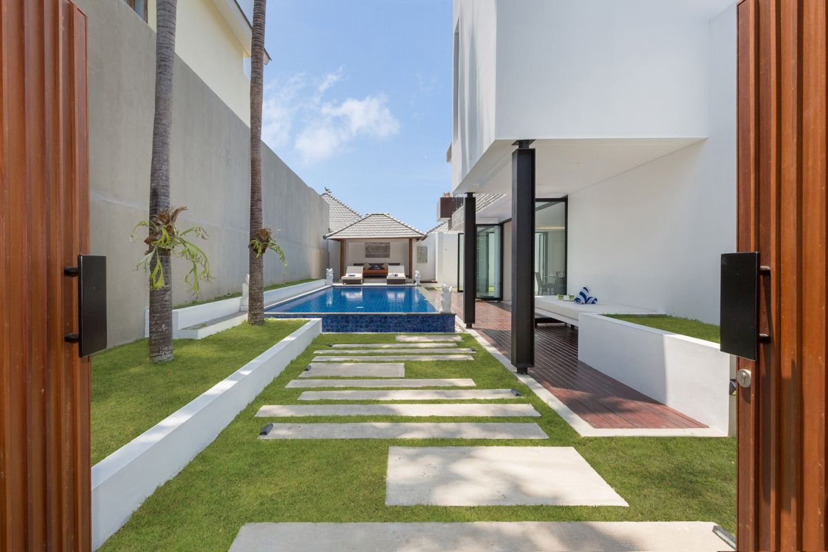 Modern white kitchen with island countertop, gas stove, stainless sink, and tropical orchid accents. - Bali Villas