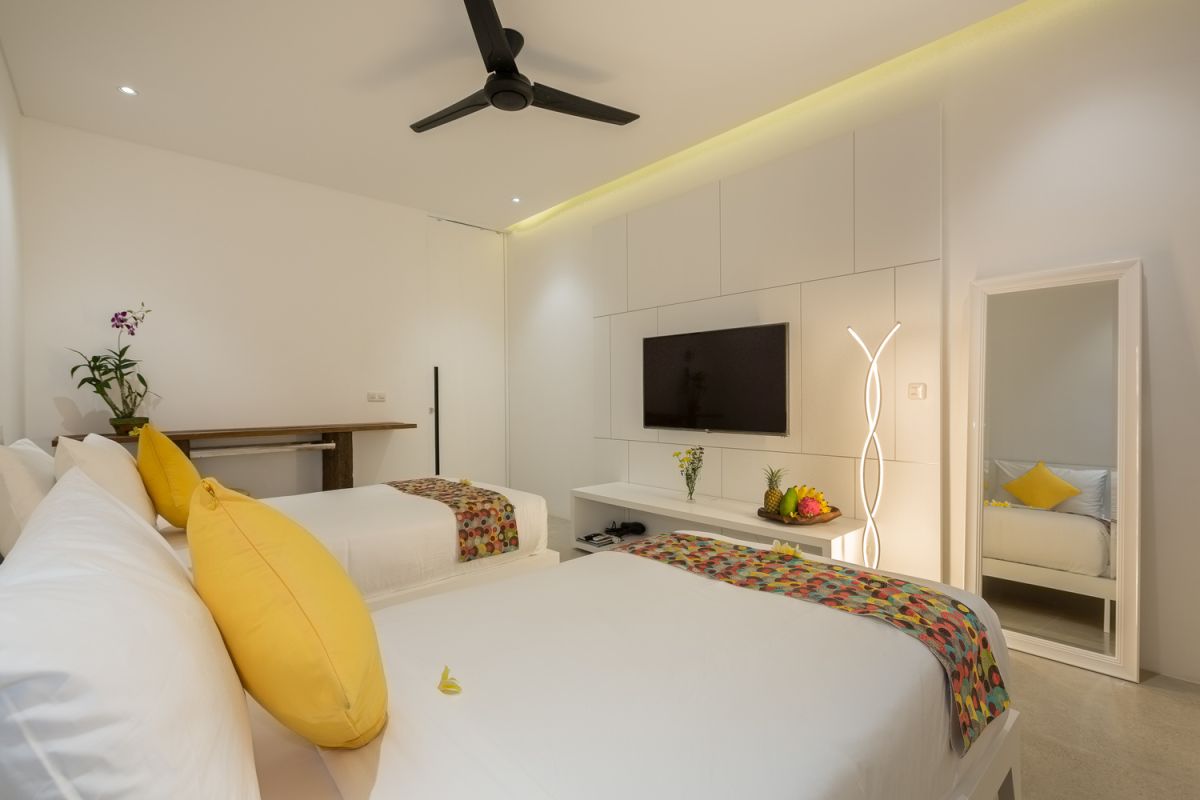 Modern white kitchen with island countertop, gas stove, stainless sink, and tropical orchid accents. - Bali Villas