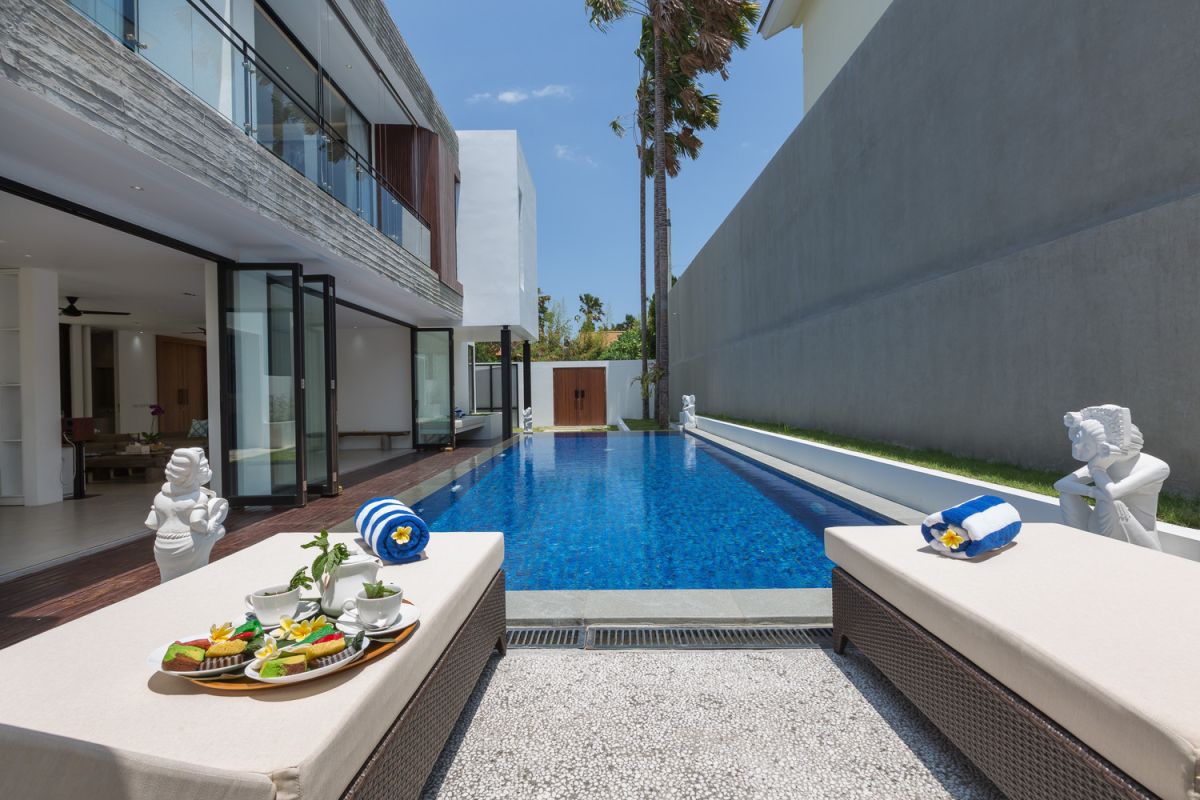 Modern white kitchen with island countertop, gas stove, stainless sink, and tropical orchid accents. - Bali Villas