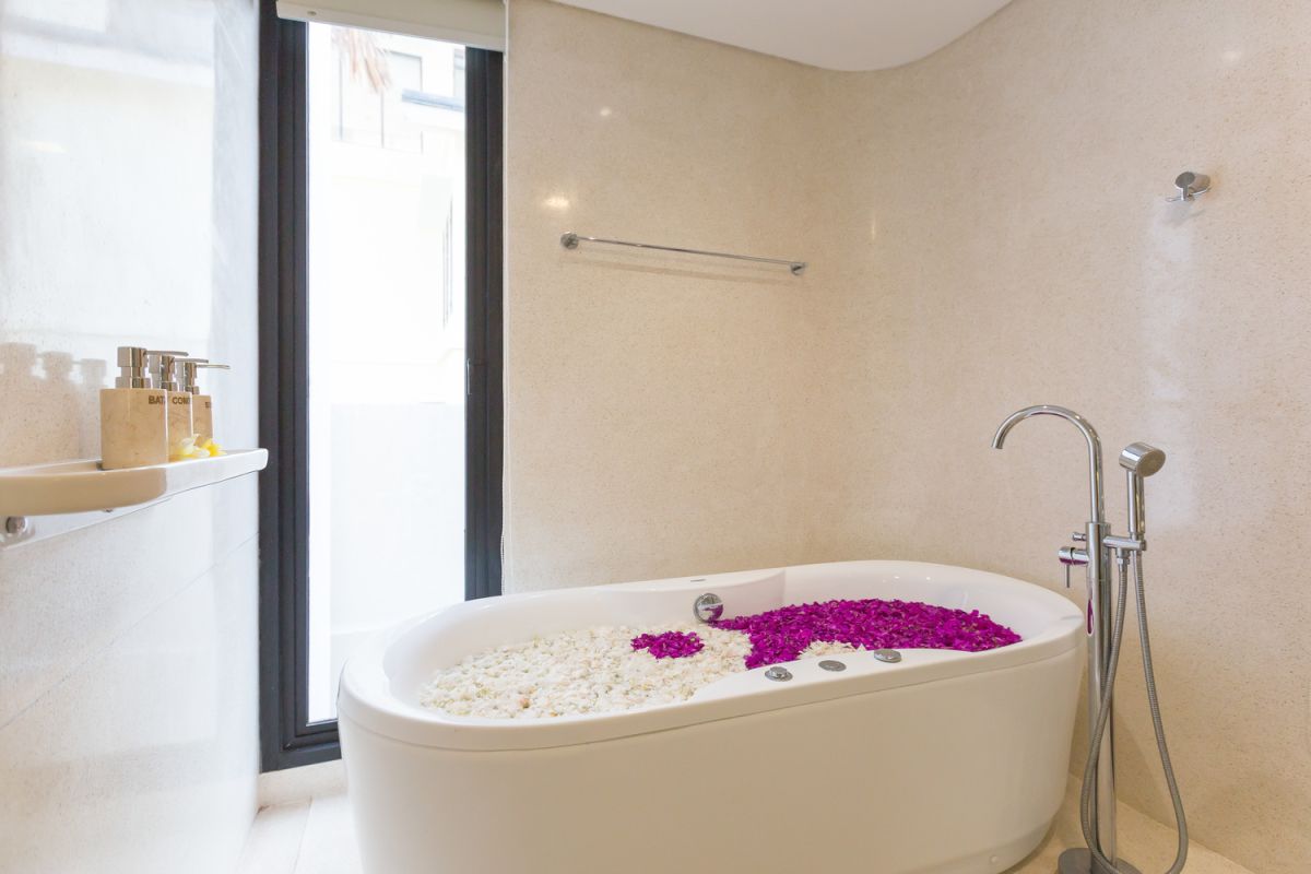 Modern white kitchen with island countertop, gas stove, stainless sink, and tropical orchid accents. - Bali Villas