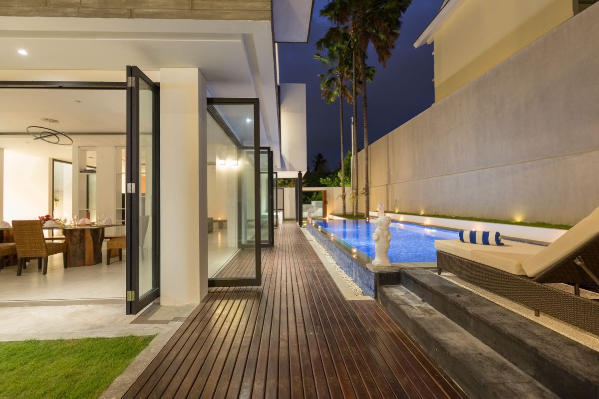 Modern white kitchen with island countertop, gas stove, stainless sink, and tropical orchid accents. - Bali Villas
