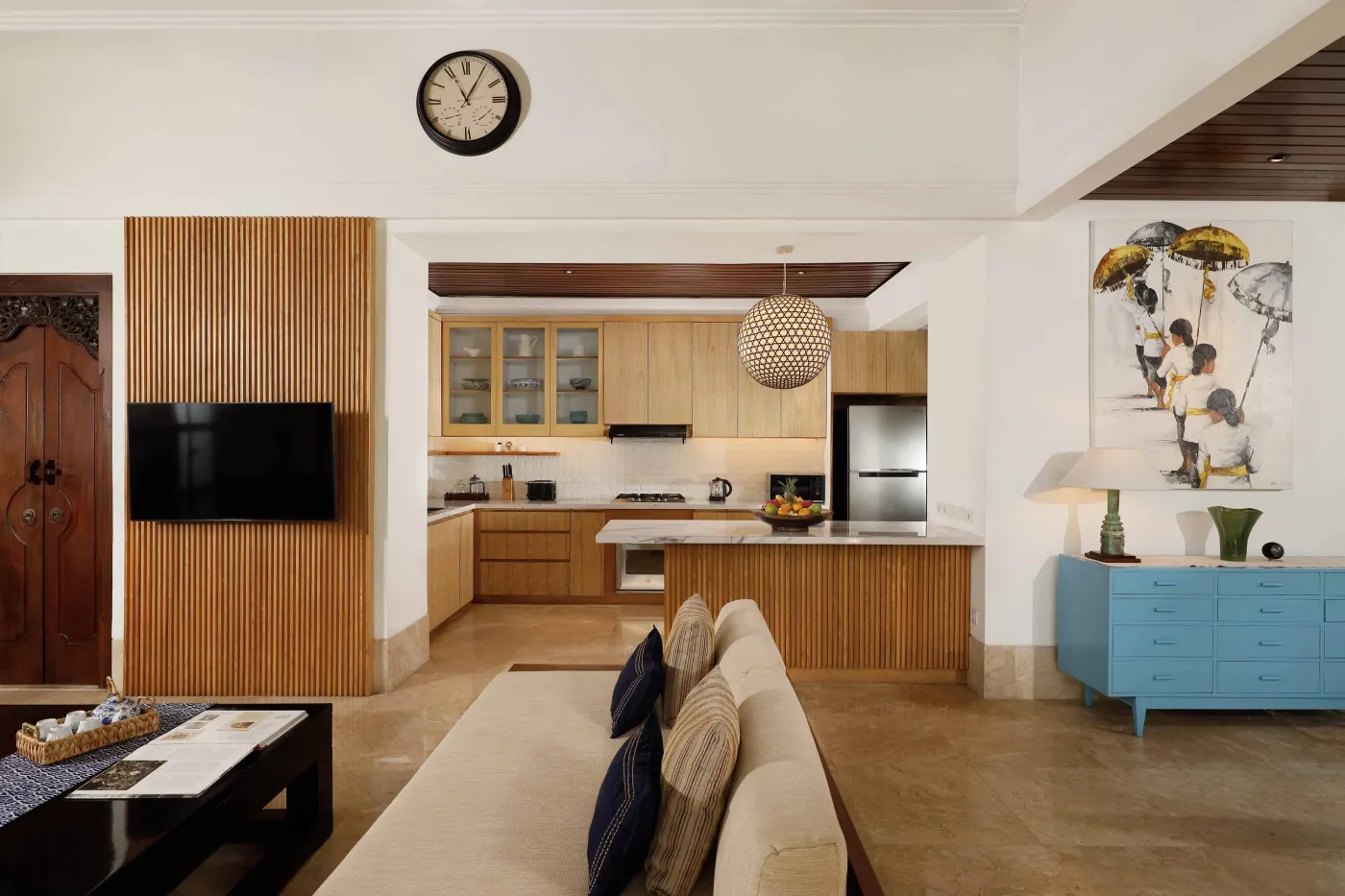 Cozy wicker chair and round table with tea set on a Balinese-style veranda, featuring thatched roof, wooden shutters, and tropical garden views. - Bali Villas