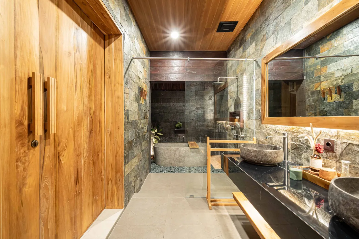 Luxurious Balinese bedroom with king bed, bamboo ceiling, lush plants, and sliding doors to private pool. - Bali Villas