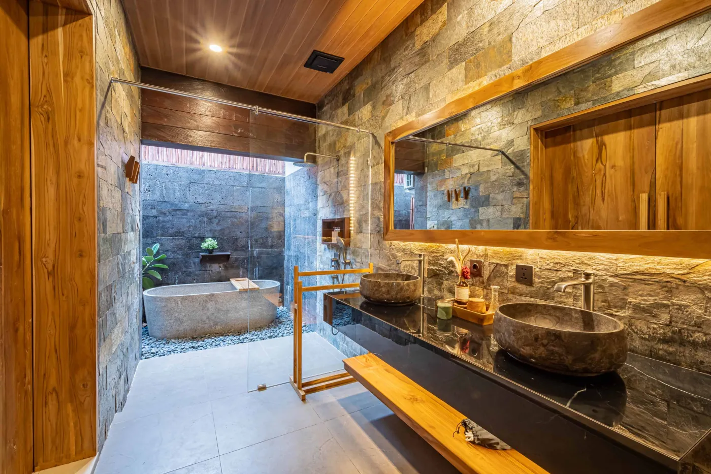 Luxurious Balinese bedroom with king bed, bamboo ceiling, lush plants, and sliding doors to private pool. - Bali Villas