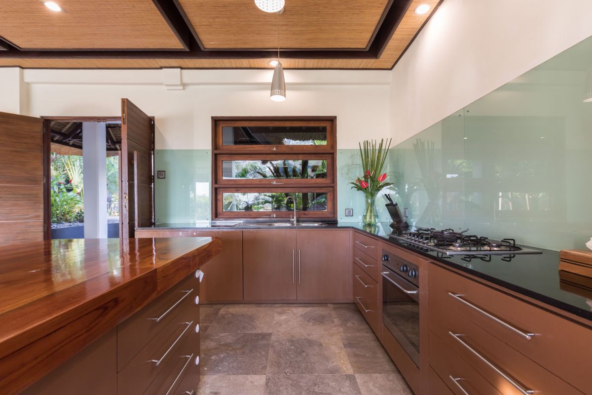 Spacious Balinese-style bathroom with tropical plants, open glass shower, white vanity, and skylight. - Bali Villas