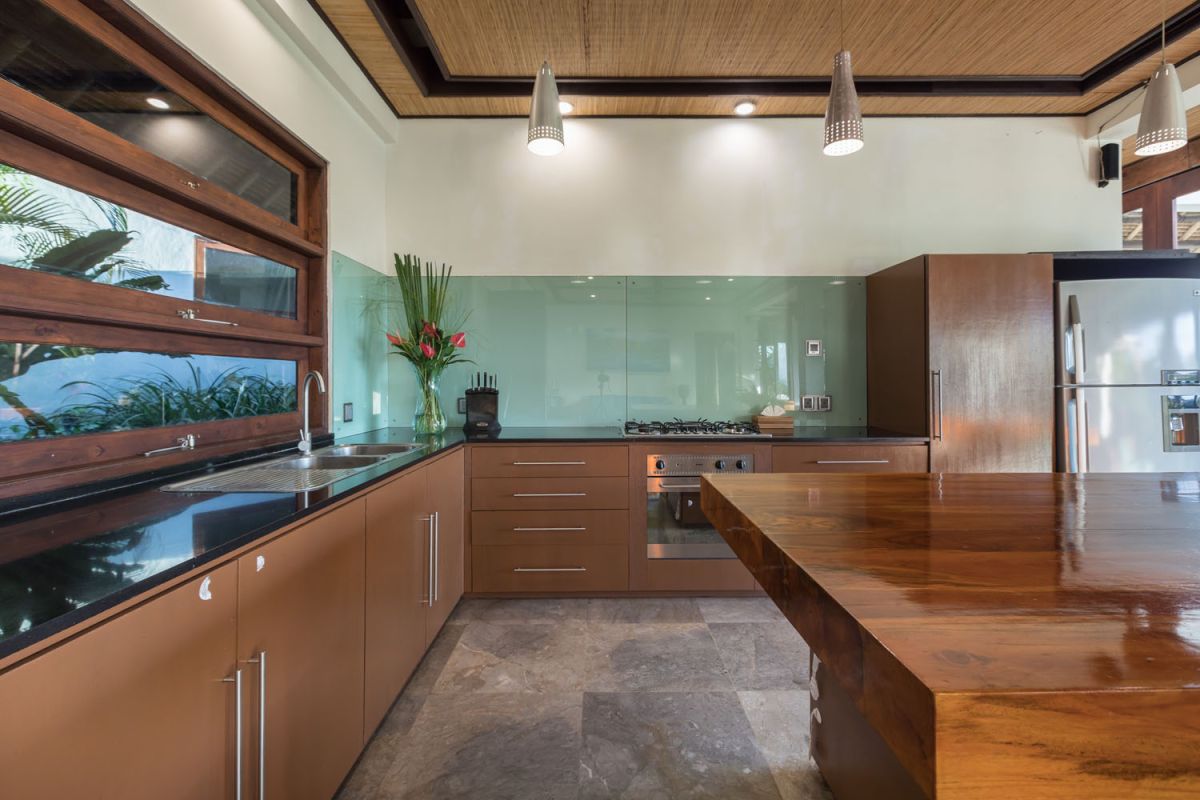 Spacious Balinese-style bathroom with tropical plants, open glass shower, white vanity, and skylight. - Bali Villas