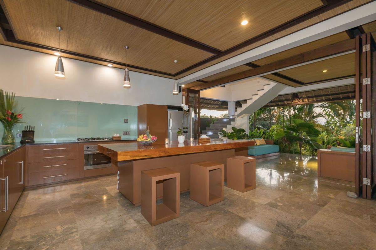 Spacious Balinese-style bathroom with tropical plants, open glass shower, white vanity, and skylight. - Bali Villas