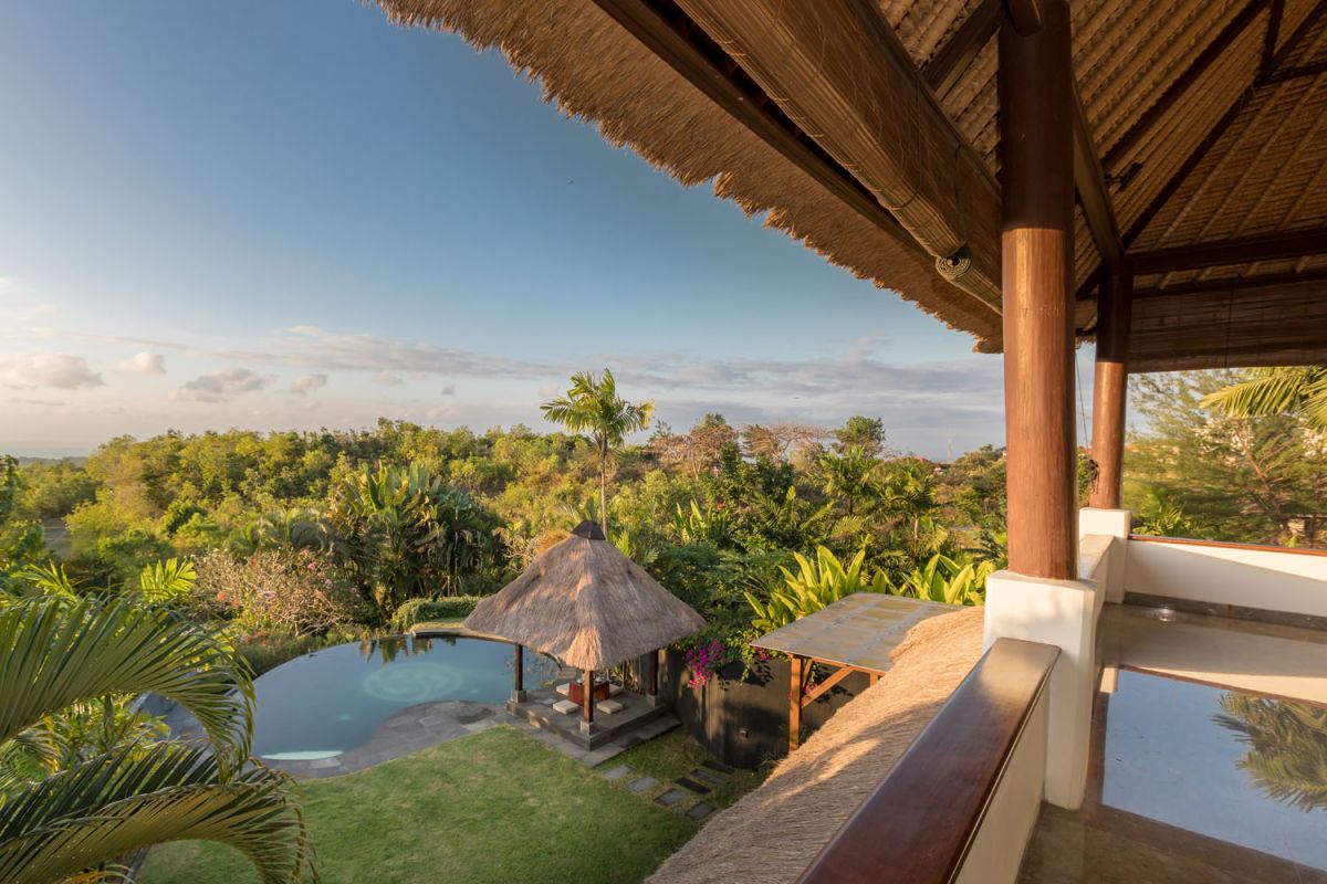 Spacious Balinese-style bathroom with tropical plants, open glass shower, white vanity, and skylight. - Bali Villas