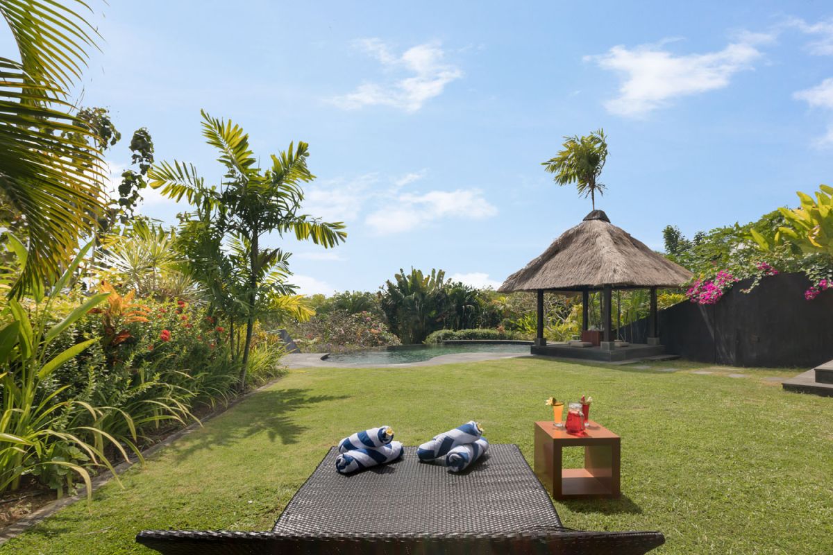 Spacious Balinese-style bathroom with tropical plants, open glass shower, white vanity, and skylight. - Bali Villas