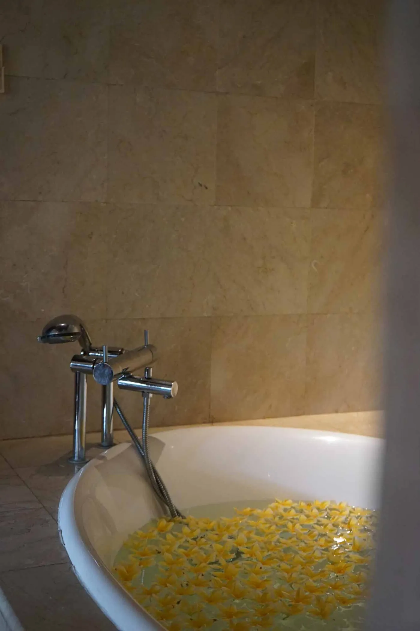 Balinese villa interior featuring a woven thatched hanging lamp, open white kitchen, and vibrant rooster wall art over a wooden dining table. - Bali Villas