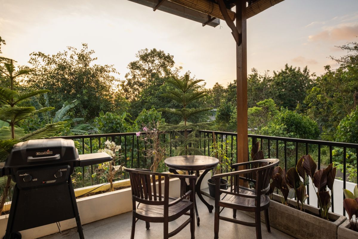 Overhead view of a private plunge pool in a tropical Bali villa, surrounded by wooden deck, lounge chairs, lush plants, and open bedroom doors. - Bali Villas