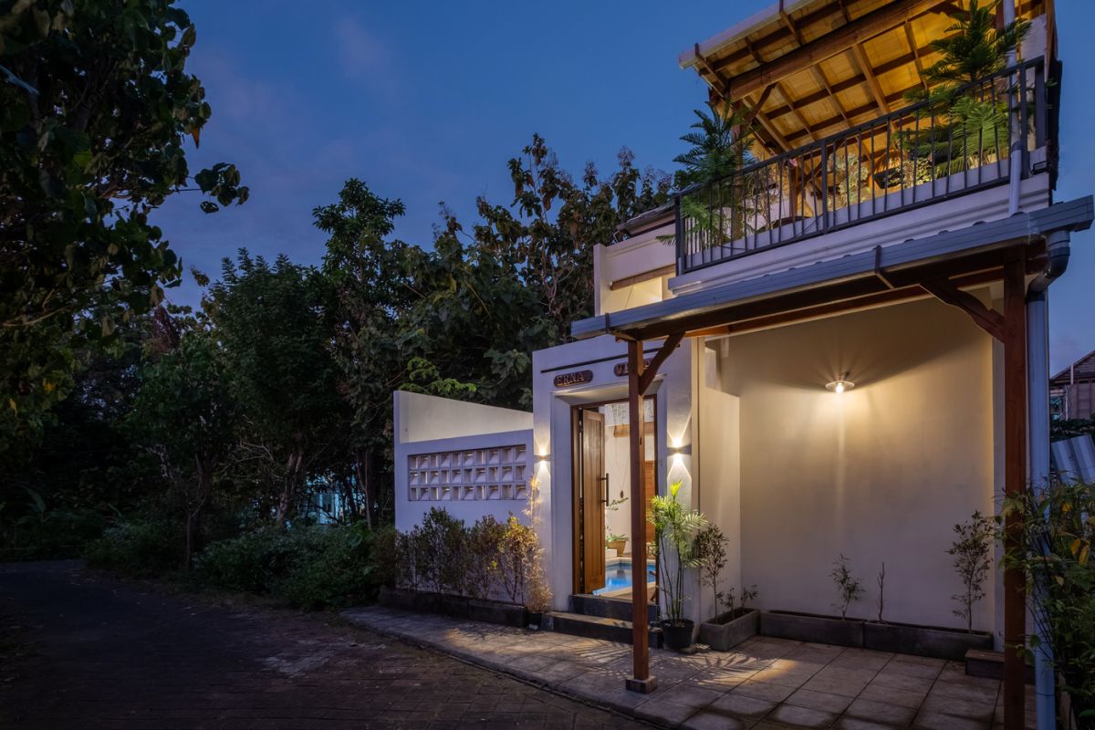 Overhead view of a private plunge pool in a tropical Bali villa, surrounded by wooden deck, lounge chairs, lush plants, and open bedroom doors. - Bali Villas