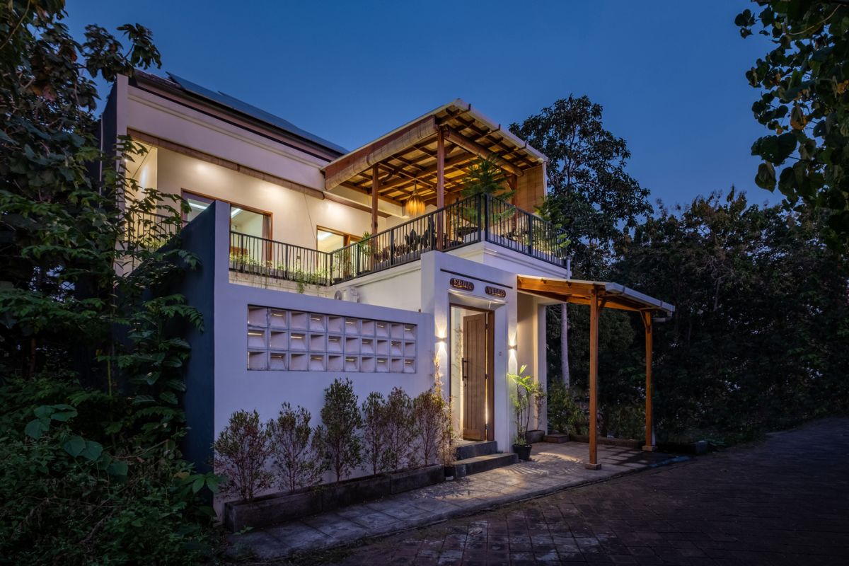 Overhead view of a private plunge pool in a tropical Bali villa, surrounded by wooden deck, lounge chairs, lush plants, and open bedroom doors. - Bali Villas