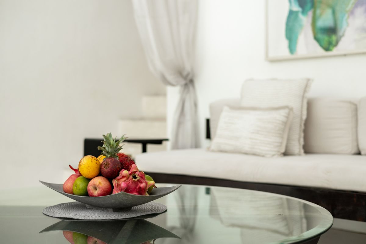 Modern white kitchen bar with concrete countertop, wooden stools, and lush tropical greenery outside arched windows. - Bali Villas
