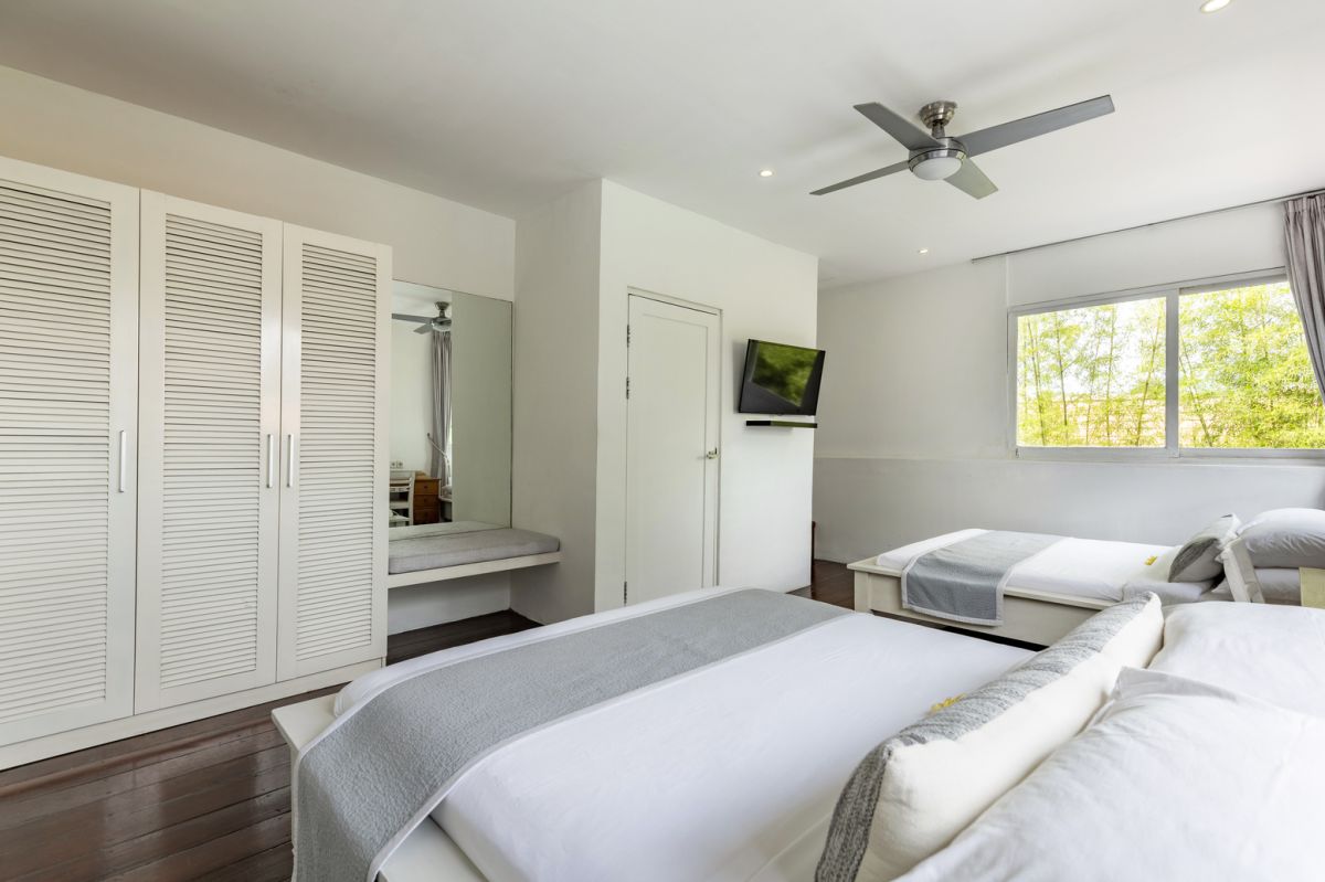 Modern white kitchen bar with concrete countertop, wooden stools, and lush tropical greenery outside arched windows. - Bali Villas
