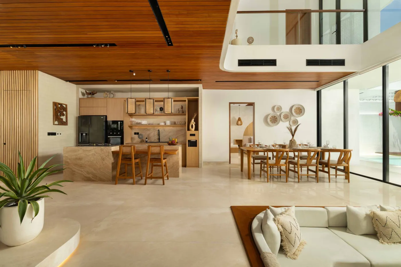Modern game room featuring a sleek black pool table with red felt, surrounded by wooden stools, under a wooden ceiling with pendant lights, large windows showing tropical greenery, and stylish wooden accents. - Bali Villas