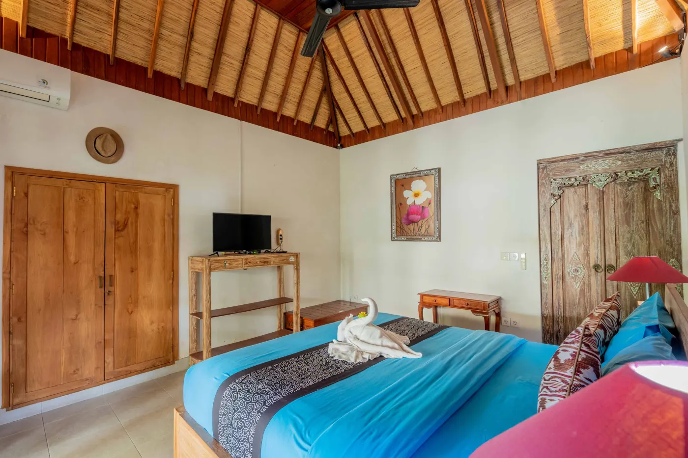 Spacious open-air Balinese pavilion with intricate carved wooden beams, hanging lanterns, rattan furniture, and tropical garden views. - Bali Villas