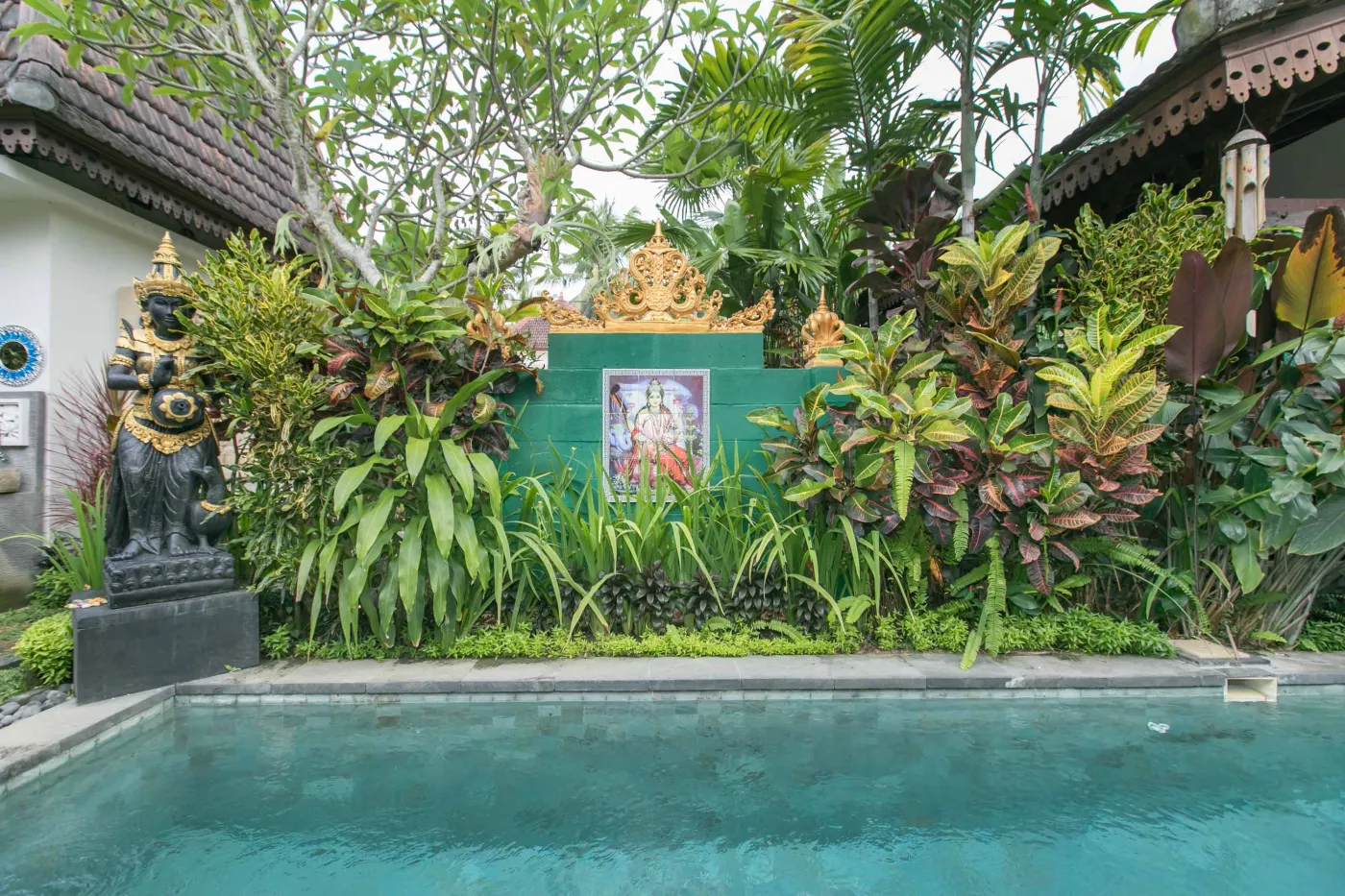 Spacious open-air Balinese pavilion with intricate carved wooden beams, hanging lanterns, rattan furniture, and tropical garden views. - Bali Villas