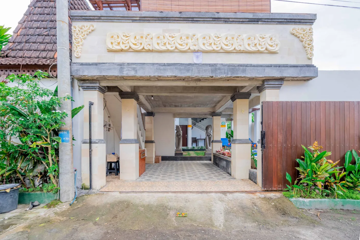 Serene Balinese villa courtyard with blue infinity pool, stone guardian statues, lounge chairs, tropical plants, and patterned tile patio. - Bali Villas