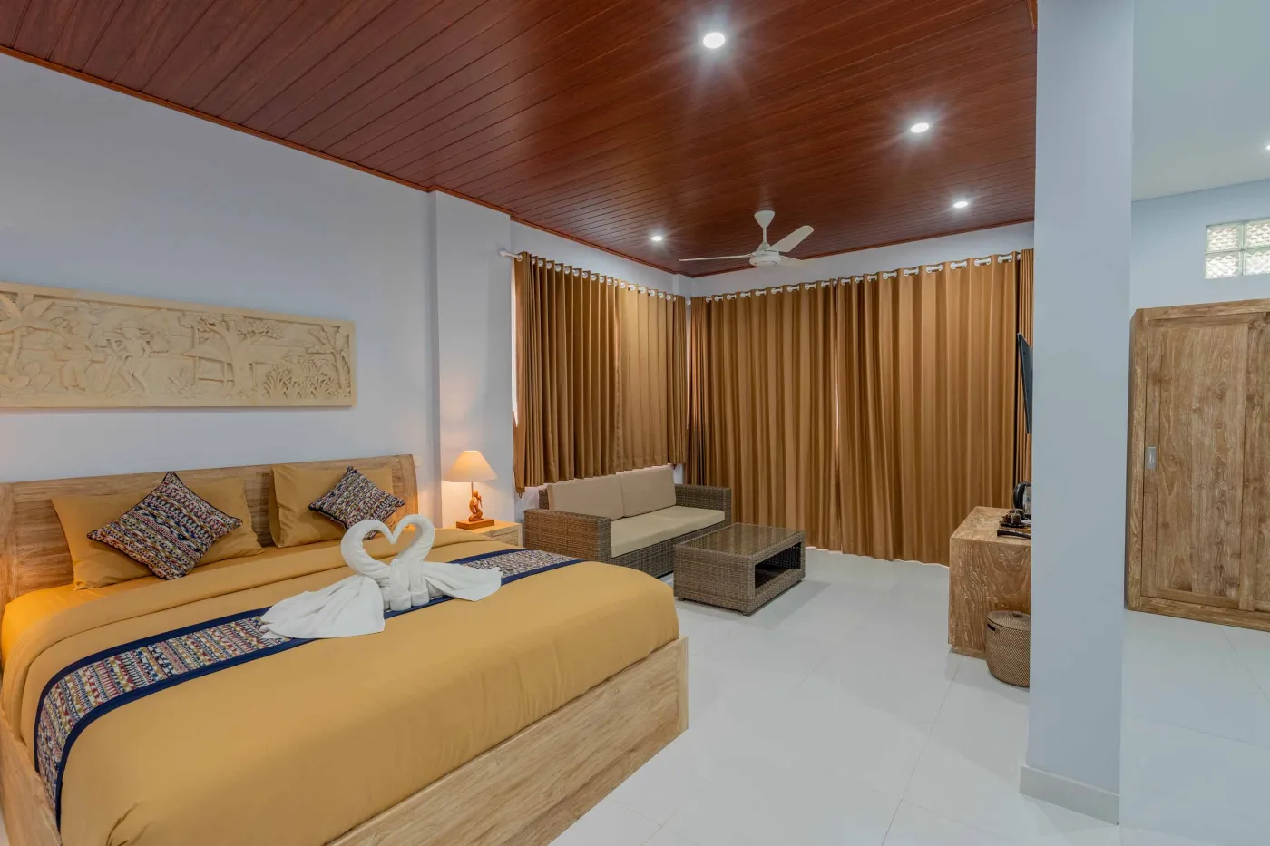 Serene Balinese villa courtyard with blue infinity pool, stone guardian statues, lounge chairs, tropical plants, and patterned tile patio. - Bali Villas