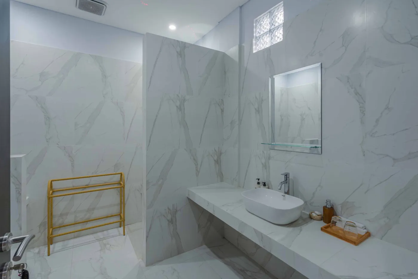 Serene Balinese villa courtyard with blue infinity pool, stone guardian statues, lounge chairs, tropical plants, and patterned tile patio. - Bali Villas