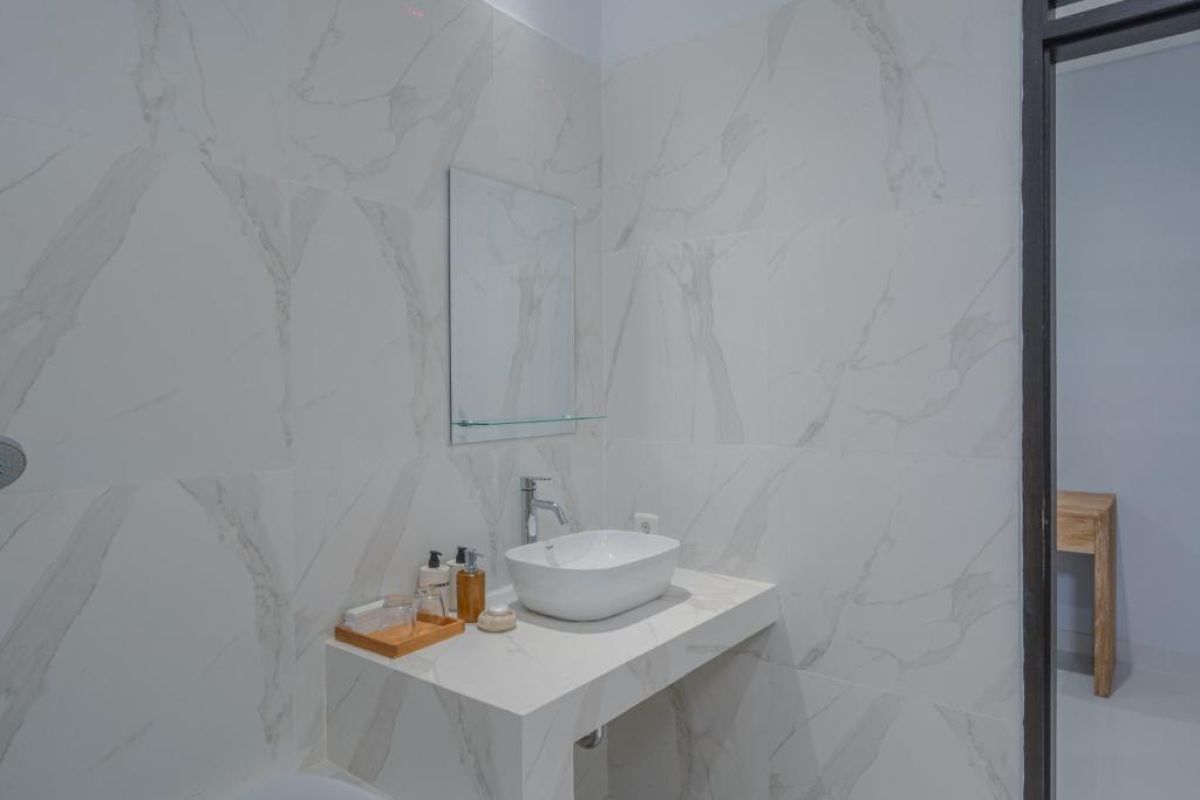 Spacious Balinese-style hotel bedroom with wooden ceiling fan, king bed, wall-mounted TV, and orange curtains. - Bali Villas