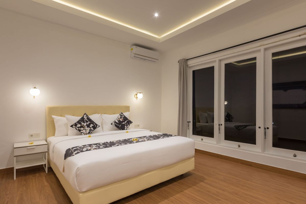Modern bathroom with black-framed glass shower enclosure, rainfall showerhead, white toilet, and marble vanity sink. - Bali Villas
