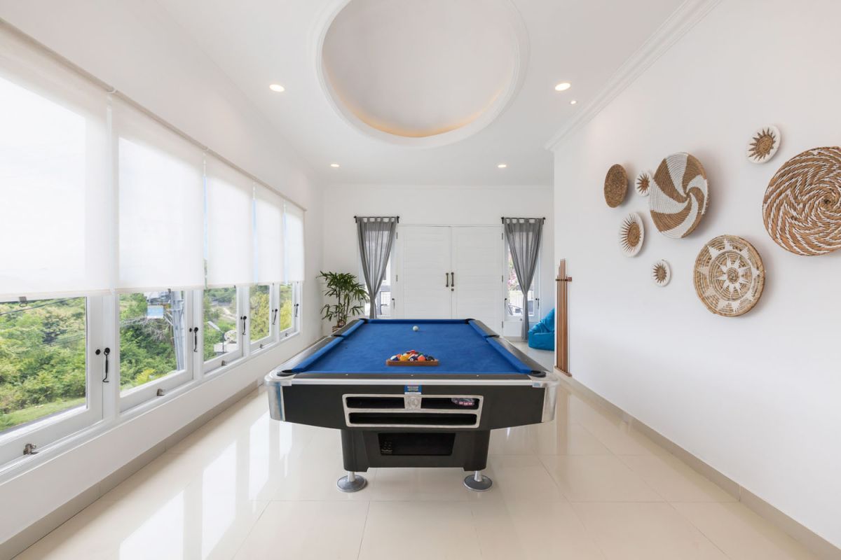 Modern bathroom with black-framed glass shower enclosure, rainfall showerhead, white toilet, and marble vanity sink. - Bali Villas