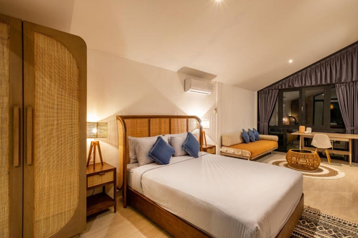 Serene tropical infinity pool at dusk with white lounge chairs, beige umbrella, and lush banana palms under soft lighting. - Bali Villas