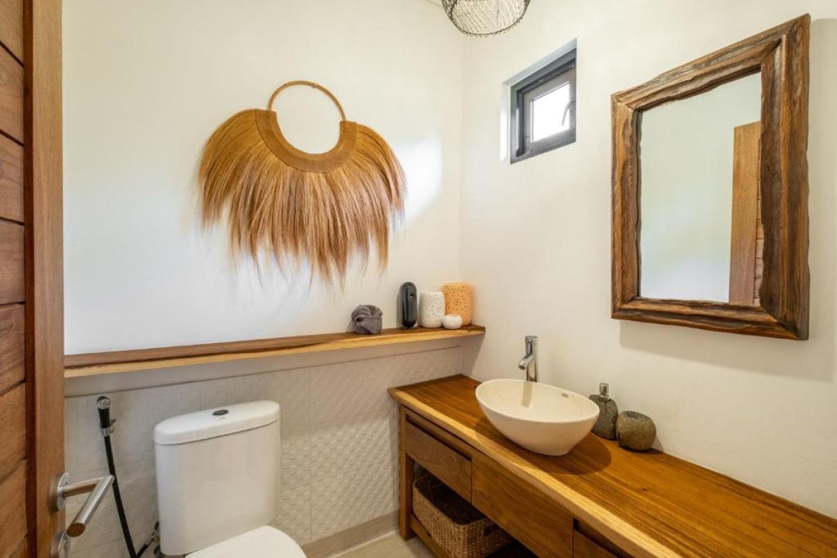 Serene tropical infinity pool at dusk with white lounge chairs, beige umbrella, and lush banana palms under soft lighting. - Bali Villas