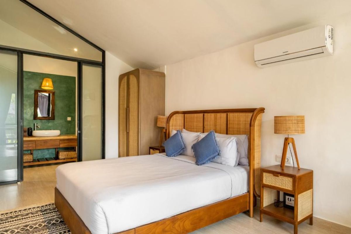 Serene tropical infinity pool at dusk with white lounge chairs, beige umbrella, and lush banana palms under soft lighting. - Bali Villas