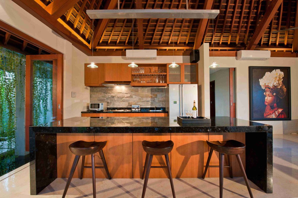 Luxurious tropical bathroom with petal-filled freestanding bathtub, lush green plants, wooden vanity, and stone shower area. - Bali Villas