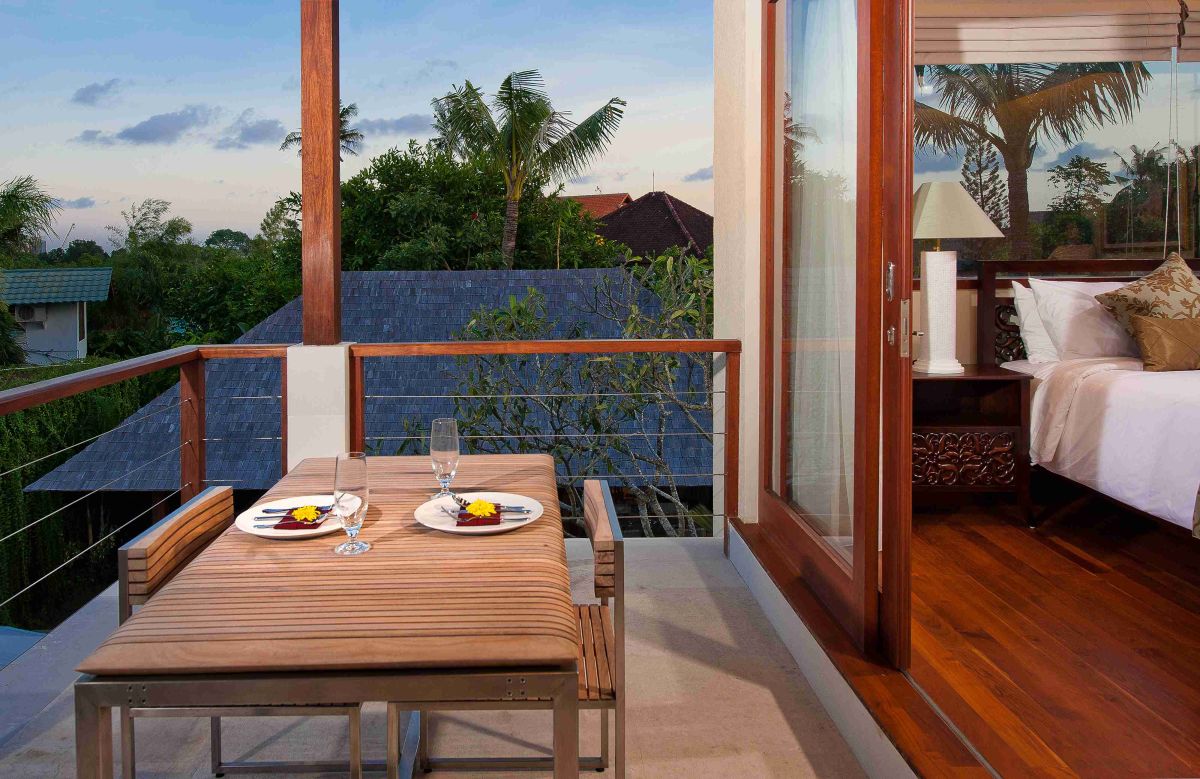 Luxurious tropical bathroom with petal-filled freestanding bathtub, lush green plants, wooden vanity, and stone shower area. - Bali Villas