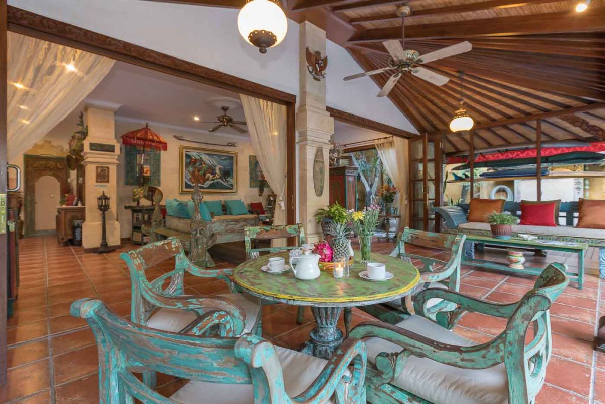 Luxurious Bali-style spa bathroom with rose-petal-filled bathtub, double black stone sinks, wooden vanities, tropical plants, and natural light from skylight. - Bali Villas