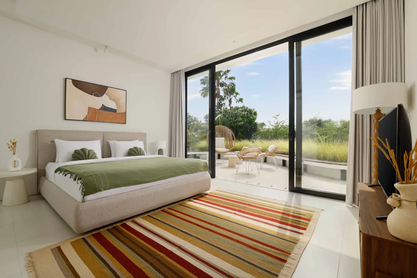 Modern minimalist bathroom with yellow flower-filled bathtub, wooden vanity, glass shower enclosure, and potted greenery. - Bali Villas