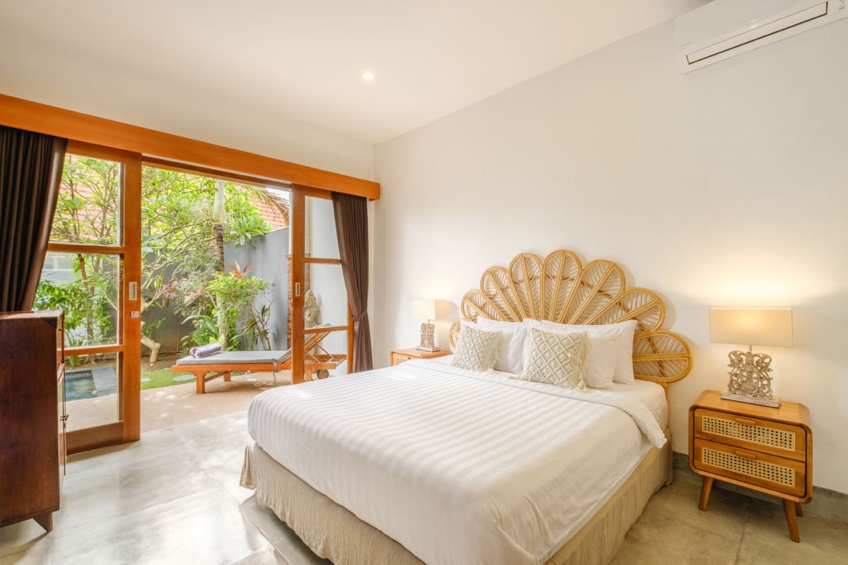 Rustic Balinese villa kitchen and dining room with wooden cabinets, stone walls, and views of traditional temple roofs. - Bali Villas