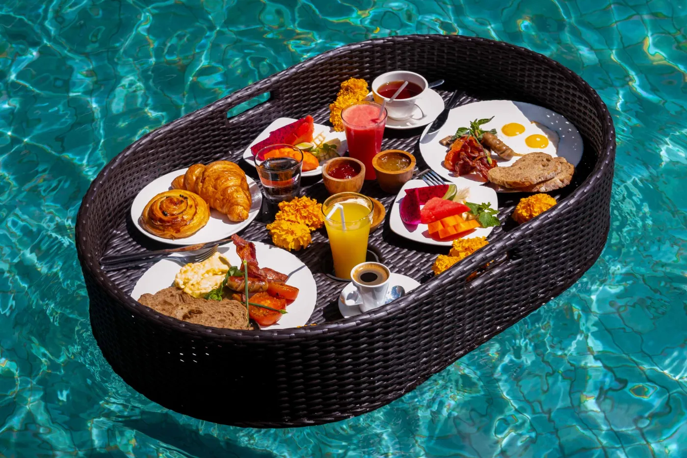 Open-air tropical resort bar with carved wooden counter, thatched roof, backlit liquor shelves, fresh fruits, and surrounding lush greenery. - Bali Villas